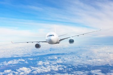 Yolcu uçakları bulutların arasında mavi gökyüzünde uçuyor.