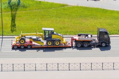 Şehirdeki otobanda uzun bir karavan platformu olan nakliye karavanının traktörü.
