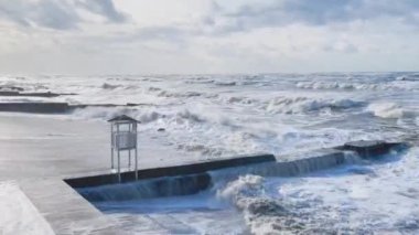 Deniz kıyısında şiddetli bir rüzgar eserken dalgalar dalgalı sularda ve sahilde bir cankurtaran botu