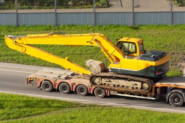 Ağır kazıcı arka rampadan alçak karavana yüklendi