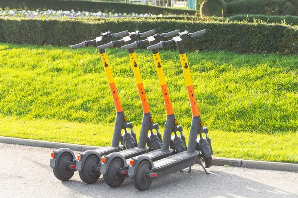 Otoparkta arka arkaya elektrikli scooterlar. Şehir bisiklet kiralama sistemi, sokakta halka açık scooter 'lar.