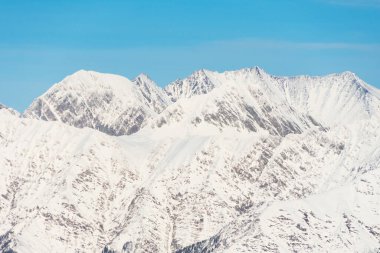 Karlı dağ manzarası, mavi gökyüzünü geçen sıradağlar.