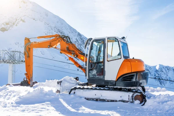 雪の山 スキー場の上に小さな掘削機 — ストック写真