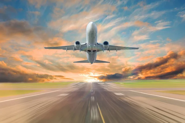 夕方の夕日の美しい空を背景に旅客用のジェット旅客機を離陸し 滑走路に移動速度の動きの影響 — ストック写真
