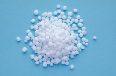 Mavi arkaplanda Urea granülleri, metin için boşluk, üst görünüm. Nitrojen mineral gübresi - ürea. Amonyum nitrat, bir amonyak tuzu ve nitrik asit bitkilerin beslenmesi için kullanılır..