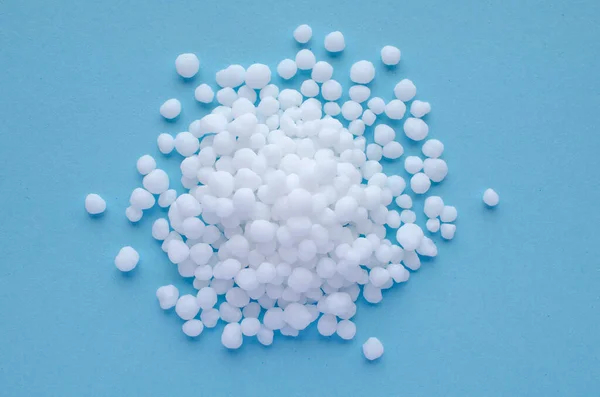 Mavi arkaplanda Urea granülleri, metin için boşluk, üst görünüm. Nitrojen mineral gübresi - ürea. Amonyum nitrat, bir amonyak tuzu ve nitrik asit bitkilerin beslenmesi için kullanılır..