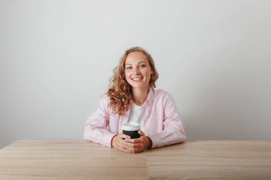 Genç güzel kız öğrenci sabah kahvesini içiyor.