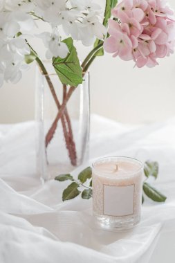 Beyaz arka planda cam bardakta mumlar olan narin bir buket. Hava dikey bileşimi