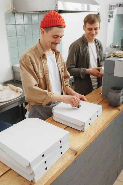 Hombres jóvenes preparan pizza fresca en la cafetería — Foto de Stock