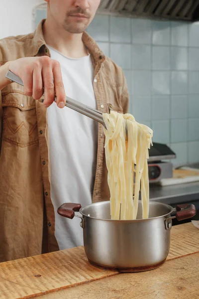 Hombre cocinar pasta fresca hecha a mano para el almuerzo — Foto de Stock