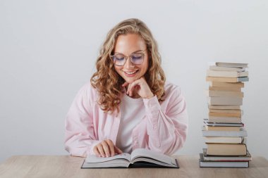 Güzel öğrenci gülümser ve bir kitap okur.