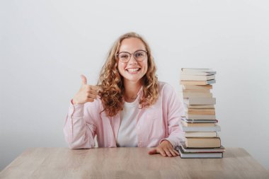 Geniş gülümsemeli, kitap okumayı seven sarışın bir öğrencinin portresi. 