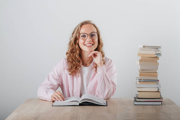 Girl in glasses and a large stack of books