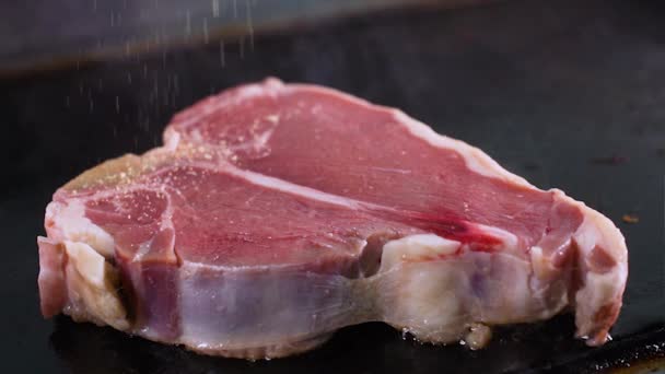 Der Koch würzt ein rohes, saftiges Schweinesteak — Stockvideo