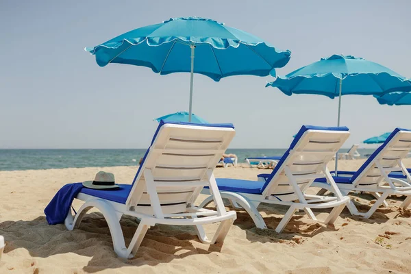 Lettini sulla sabbia vicino al mare e ombrelloni Immagine Stock