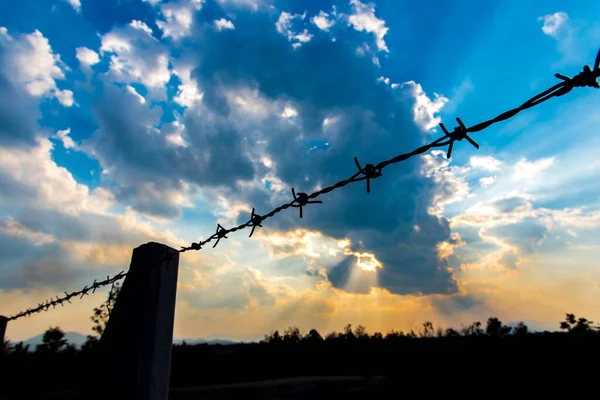 Barbed wire fence with silhouette sky and cloud