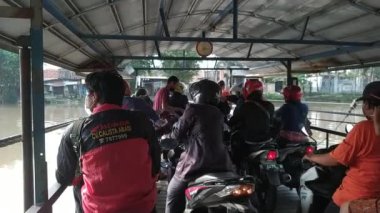 İnsanları taşıyan ve bisikletle Endonezya 'da nehri geçen geleneksel motorsuz feribot.