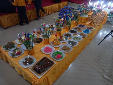 Medan, Endonezya-23 Ocak 2022: Geleneksel Kuzey Sumatra Malezya düğününde gelin ve ailesinin önünde geleneksel bir pirinç yeme töreni yapılır. Sağlanan yiyecekler çeşitlidir & col