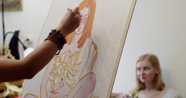 Gezichtsloze kunstenaar maakt portret van jong meisje poseren op de bank in studio natuurlijk daglicht. Schattig model zittend binnen en vrouw tekening tekening kunstwerk thuis. Werkplaatsconcept voor hobby 's — Stockvideo