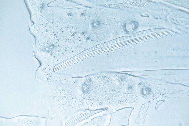 Bubble gel texture. Natural gel texture. Transparent liquid gel spot on blue background. Textured smear with oxygen bubbles. Clear liquid gel bubbles texture. Face serum, hand santizer swatch