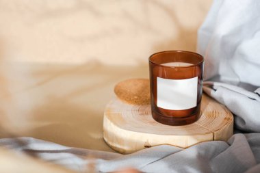 Meditation space with candle. Burning candle on wooden coaster. Warm aesthetic composition with dry boho branch and grey fabric. Home comfort, spa, relax and wellness concept. High quality photo