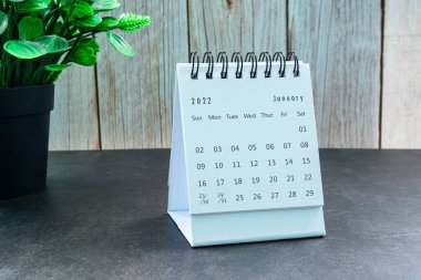 Beyaz Ocak 2022 takvimi ve tahta masa üzerinde saksı bitkisi