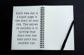 Motivační a inspirativní citace na bílém notebooku přes tmavé pozadí