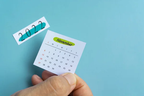Ruka držící bílý listopadový kalendář s pozadím notepadu rok 2022 — Stock fotografie