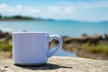 Bulanık plaj arka planında boş beyaz bardak. Boşluğu kopyala