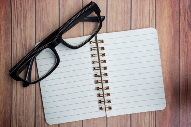 Tahta masada, okuma gözlüğü ve kalemi olan not defteri. Tam üstte. Düz yatıyordu.