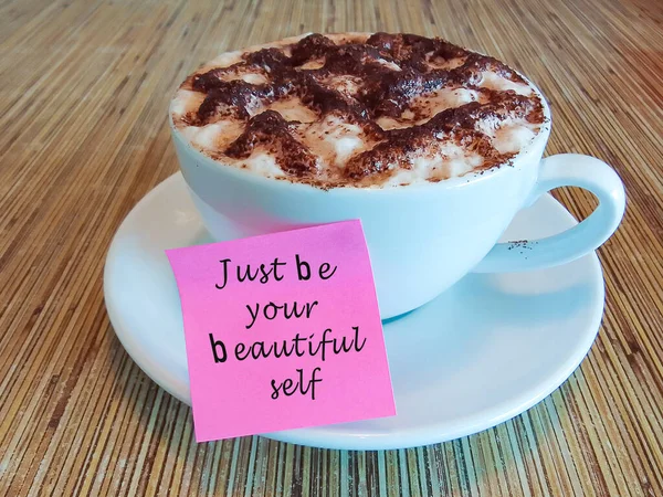 木製の机の上のコーヒーカップのピンクのノートのモチベーションとインスピレーションの引用 ちょうどあなたの美しい自己である — ストック写真