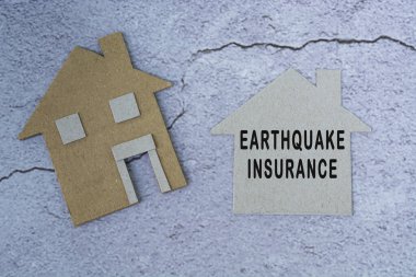 Kağıt ev modeli üzerine deprem sigortası metni. Ev sigortası konsepti. Düz yatıyordu. Tam üstte.