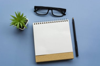 Not defteri, saksı bitkisi, kağıt kalem ve gözlüklü. Düz yatıyordu. Tam üstte. Metin amacı için.