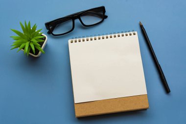 Not defteri, saksı çiçeği, kalem ve gözlüklü. Düz yatıyordu. Tam üstte. Metin amacı için.