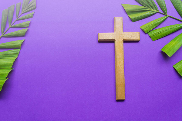 Good Friday, Palm Sunday, Ash Wednesday, Lent Season and Holy Week concept. Cross and palm leaves on purple background.