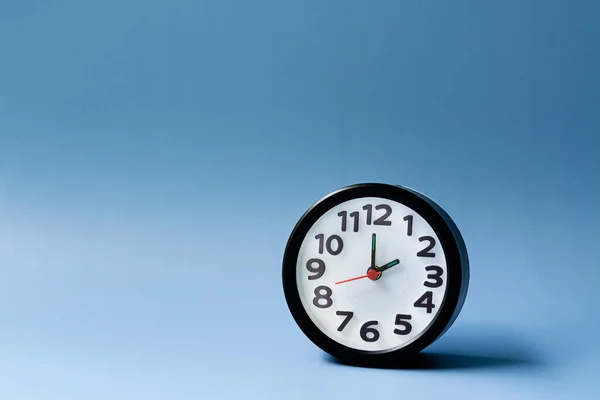 Черный будильник изолирован на синем фоне. Часы на 2 октавах. — стоковое фото