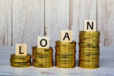 Ahşap bloklarda altın sikkeler ve ahşap bir masa üzerinde kredi metni. Finansal ve ipotek kavramı.