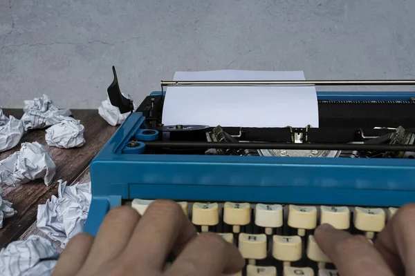 木製の机の上に古いタイプライターとゴミの紙をタイプするビジネスマンの手 — ストック写真