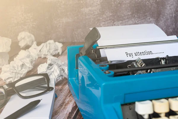 木製の机の上の古い青いタイプライターとゴミ箱の紙に入力されたテキスト 注意を払う — ストック写真