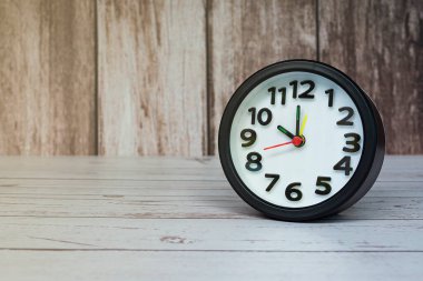 Ahşap masada siyah çalar saat izole edilmiş. Saat 10 'a ayarlandı. Son teslim tarihi kavramı.