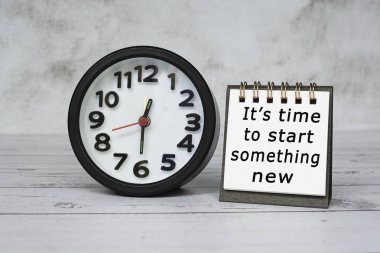 Siyah alarmlı not defterindeki motivasyon metni saat 12: 30 'da ahşap masaya kurulur..