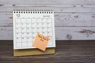 Aralık 2022 takvimi ahşap masa üzerinde tarih çemberi ve yapışkan notlar üzerine metin. Yeni yıl arifesi 31 Aralık 2022.