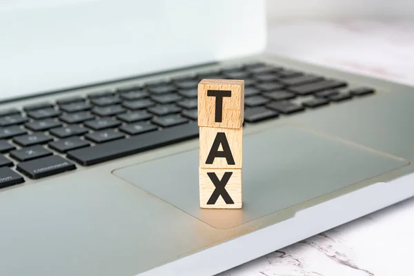 Text daně na dřevěné kostky umístěné na notebooku nebo notebooku. Koncept daně. — Stock fotografie