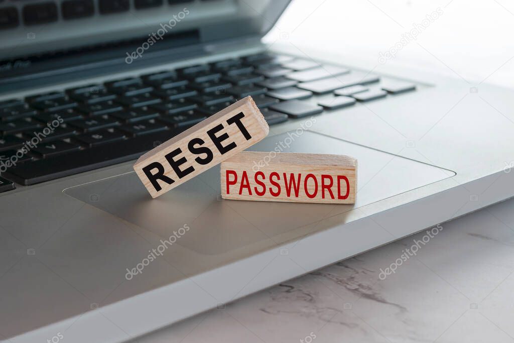 Reset password text on wooden block cube placed on laptop or notebook.