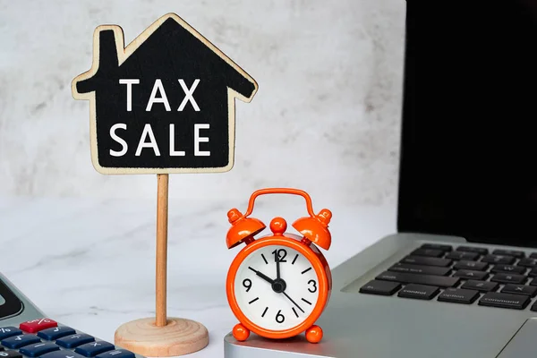 Daňový prodej textu na dřevěný dům modelu s na bílém stole. Koncept daně z nemovitosti. — Stock fotografie