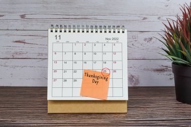 Kasım 2022 takvimi ahşap masa üzerinde tarih çemberi ve yapışkan notlar üzerine metin.