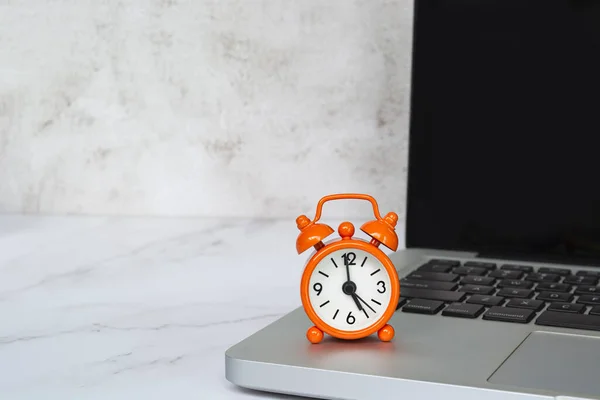 Alarm clock isolated on laptop or notebook. The clock set at 5 o\'clock. Business and deadline concept.