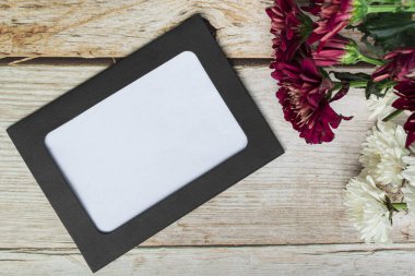 Tahta çerçeve ve çiçekler ahşap masada. Doğrudan üstte, düz yerde, boşluğu kopyala.