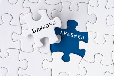 Lessons learned text on Jigsaw Puzzle over dark blue background. clipart