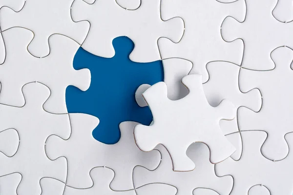 Piece of jigsaw puzzle on blue paper. Flat lay, Directly above. Copy space.